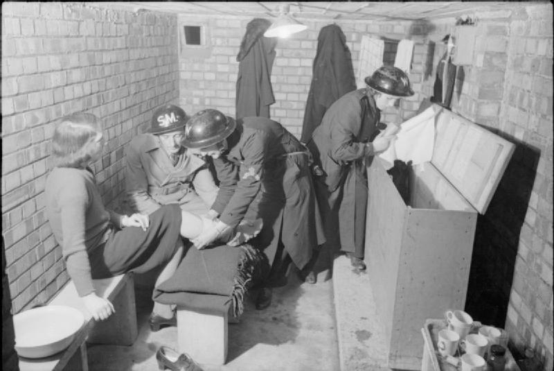 Abrigo antiaéreo em Londres durante a Segunda Guerra, com agente da ARP prestando primeiros socorros, 1940.