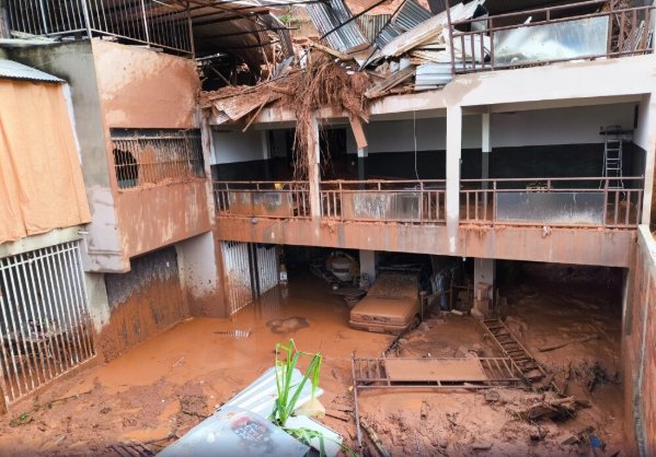 Interior de garagem residencial destruído pela lama após enchente, ilustrando um cenário de calamidade pública.